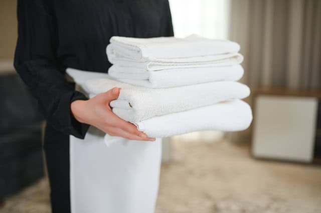 Neatly arranged white hotel linens on a luxury bed